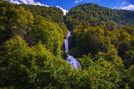 Multi-tiered Giessbach Waterfalls cascade through dense green forest near Lake Brienz, Switzerland.の写真素材