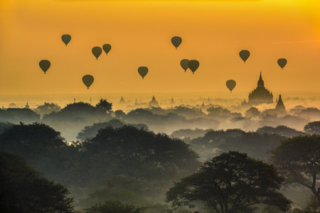 Hot air balloons float above the ancient temples of Bagan at sunrise in Myanmar.の写真素材
