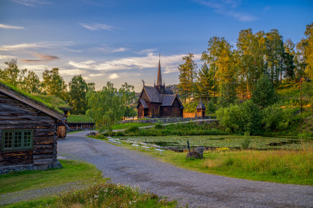 Historic Garmo Stave Church, also known as Garmo stavkirke, surrounded by traditional log buildings and forested sunset landscape in Lillehammer, Norway.の写真素材