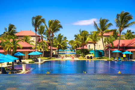 Bel Ombre, Mauritius - February 25, 2025 : Tamassa Bel Ombre resort pool surrounded by palm trees, loungers, and colorful buildings on Mauritius south coast.のeditorial素材