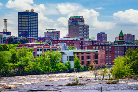 Manchester, New Hampshire, USA - June 04, 2025 : Cityscape of Manchester, New Hampshire, with urban buildings and the Merrimack River in the foreground.のeditorial素材