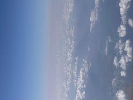 Clouds in the blue sky as seen through window of an aircraft