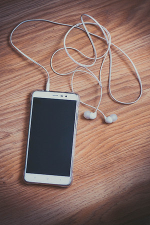 Smartphone with headphones on a wooden surfaceの写真素材