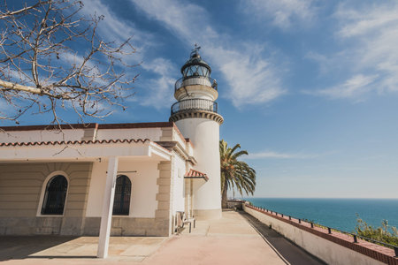 A lighthouse in front of the calm waters of the mediterranean sea. It's a sunny day of winter in the coast of Calella in Catalonia, Spain.の写真素材