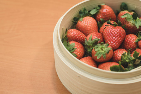 A basket full of beautiful strawberries on top of a wooden table. They are at the perfect point of maturation.の写真素材