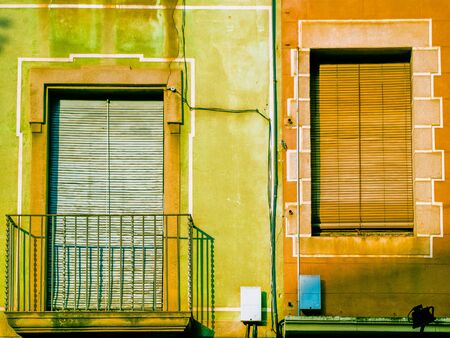 Two windows with the shutter closed on one green and one pink wall.の写真素材