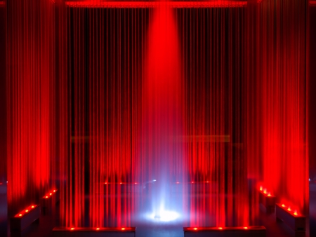 Fountain, red illuminated flowing water by night, abstract as backgroundの写真素材