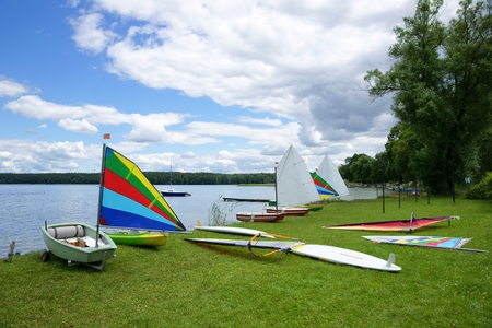 Sailing, sailboats Optimist and Windsurfing Boards, stretched out on the shore of the lakeの写真素材