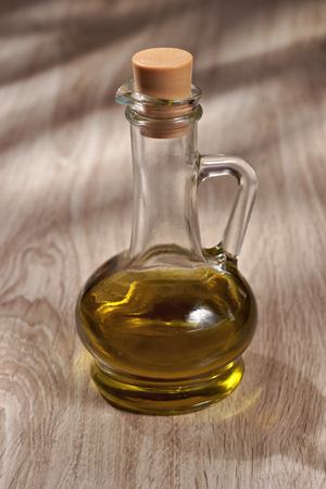 Olive oil in a glass bottle on a wooden tableの写真素材