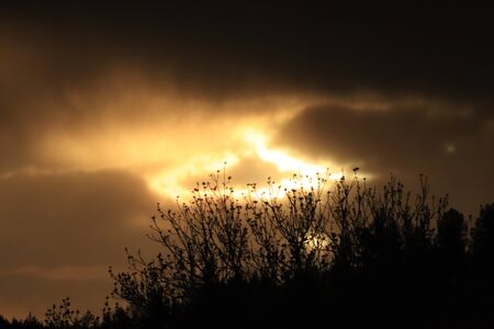 a ray of sun against a background of black cloudsの写真素材