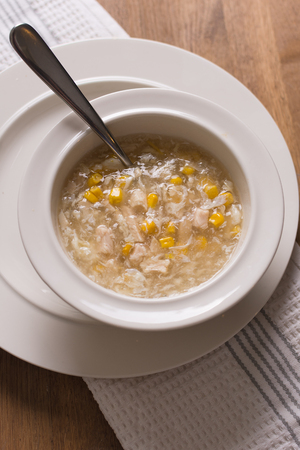 chicken sweetcorn soup in a bowl with a spoonの写真素材