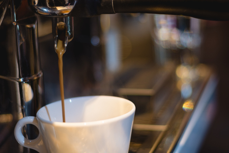 caramel coffee pouring from coffee machine into a cup in coffee shopの写真素材