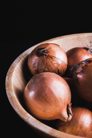 raw onions in a wooden bowl, black backgroundの写真素材