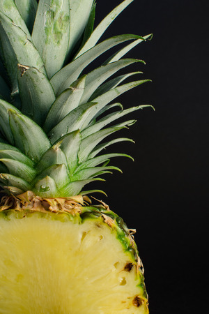 sliced pineapple fruit closeup on black backgroundの写真素材