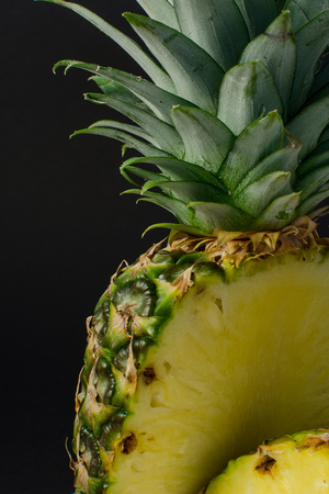 sliced pineapple fruit closeup on black backgroundの写真素材
