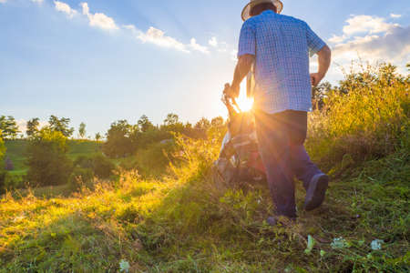 Summer Farm Scenic. Seniour man operating Sickle-bar mower in the filed