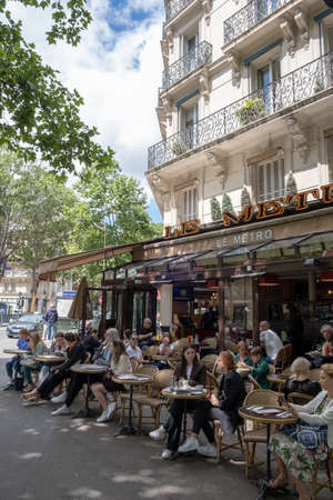 PARIS, FRANCE - JUNE 6, 2022: Tourists and Parisians enjoying a beautiful day on the streets of...
