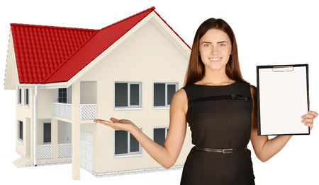 Woman standing and holding a clipboard pointing to the country house.の写真素材