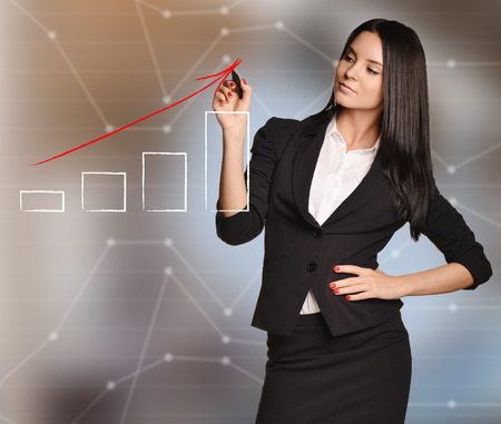 Girl draws arrow of growth over bar graph.の写真素材