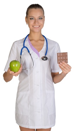 Woman doctor holding an apple and chocolate symbolize proper nutrition, diet.の写真素材