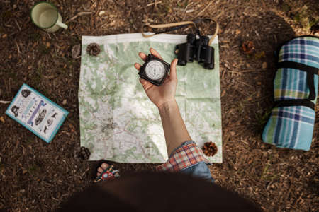 a girl is holding a compass to orientate in the forest with a map.の写真素材