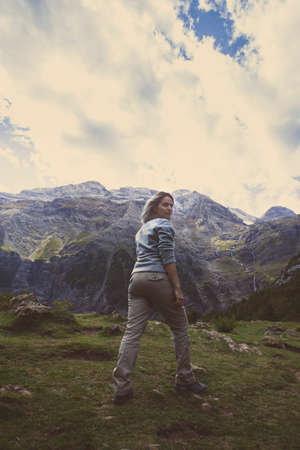 A girl hiking in a valley watches the mountains in a cloudy day.の写真素材