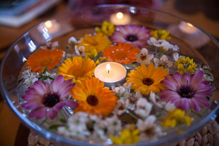 Spa glass bowl with gerbera flowers and candle floating in the water.の写真素材