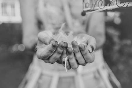 Dirty woman hands with feathers. Artistic picture. Povertyの写真素材