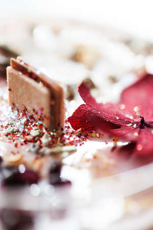 Detail of a dried red flower on glitter vegan soy candle with a wooden wick.