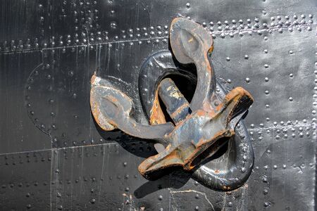 rusty anchor of a black ship in harborの写真素材