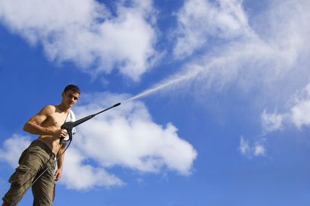 Caucasian man standing with water hose on the sky backgroundの写真素材