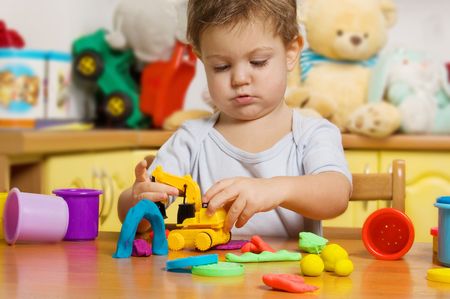 2 years old child playing plasticine in children's roomの写真素材