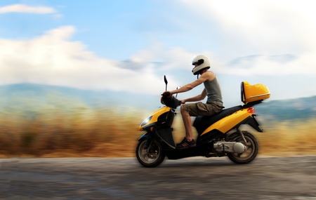 Young man riding yellow motorbikeの写真素材