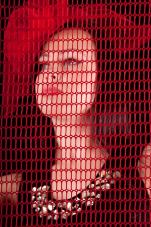 Young attractive woman behind the red grid