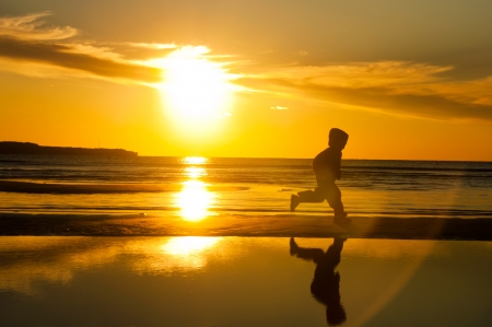 Silhouette of a child running on the beachの写真素材