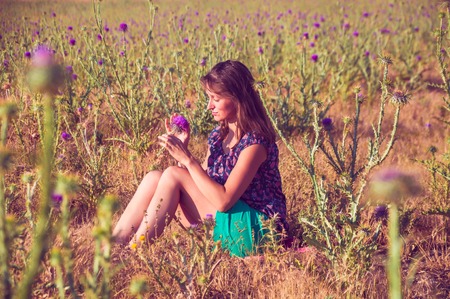 Romantic woman sitting on the stone in the field, autumn seasonの写真素材
