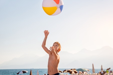 A child playing with beach ball near the sea