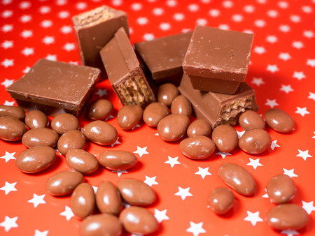 Pieces of chocolates on red background. Chocolate sweets.