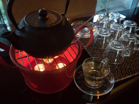 brown teapot standing on a pink steel heater with a candles and glass  tea mugの写真素材