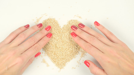 Closeup of womans hands forming heart from quinoa seedsの写真素材
