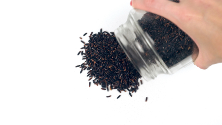 Closeup view pouring black rice from glass jar and making heart shape from itの写真素材