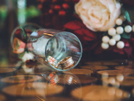 Closeup of golden wedding rings in decorative champagne glass on table of glass and wood