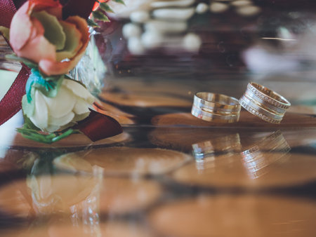 Closeup of golden wedding rings in decorative champagne glass on reflective design tableの写真素材