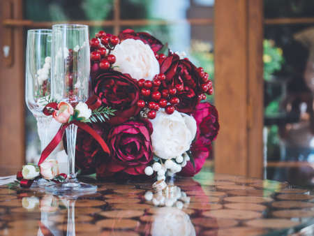 Closeup of golden wedding rings in decorative champagne glass on table of glass and woodの写真素材