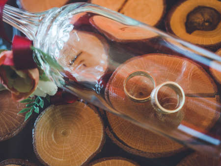 Closeup of golden wedding rings in decorative champagne glass on table of glass and woodの写真素材