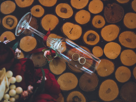 Closeup of golden wedding rings in decorative champagne glass on table of glass and woodの写真素材