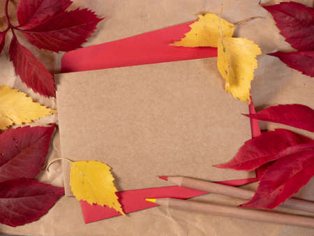 Empty retro style paper on red envelope with autumn leaves around. Flat lay, top viewの写真素材