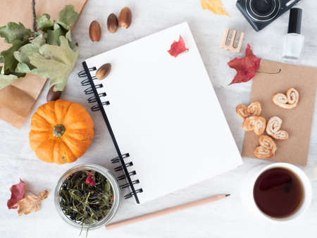 Top view of office workspace with open empty white spiral notepad, autumn leaves, decorative...