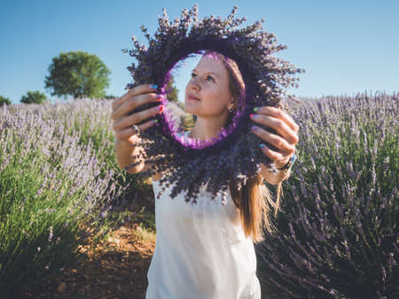 Closeup of woman hands with colorful manicure holding lavender wreath outdoors
