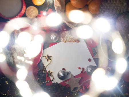 Flat lay composition with Christmas decor and blank card with space for text. Decorative lights in bokehの写真素材